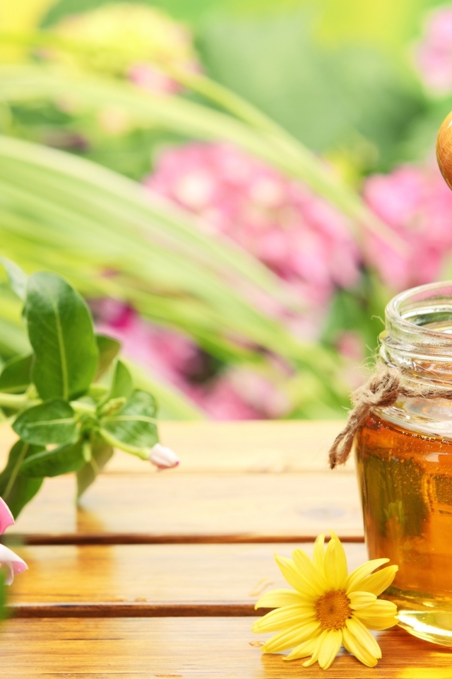 Банка ароматного меда на столе с цветами