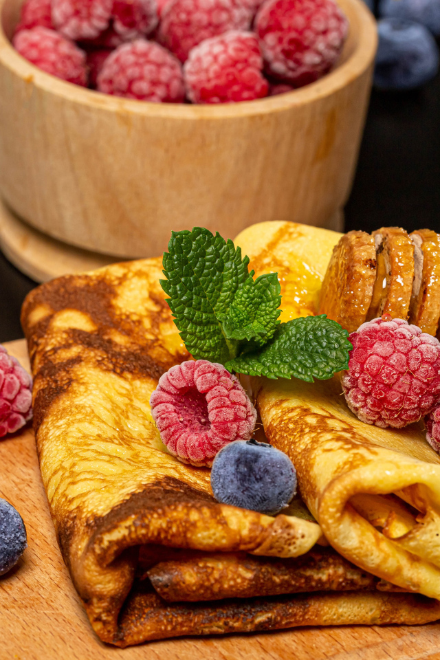 Аппетитные блины с малиной и черникой на столе