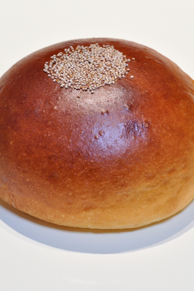 Аппетитная круглая булочка на сером фоне