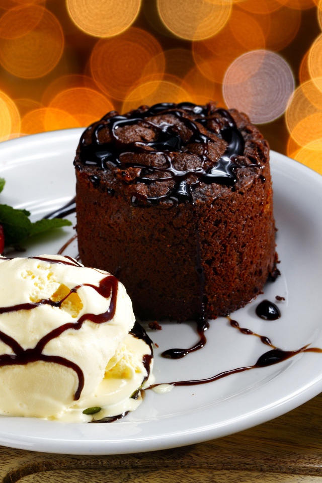 Шоколадный десерт с мороженым и клубникой на белой тарелке 