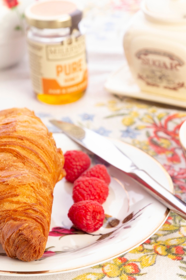 Круассан на тарелке со свежей малиной