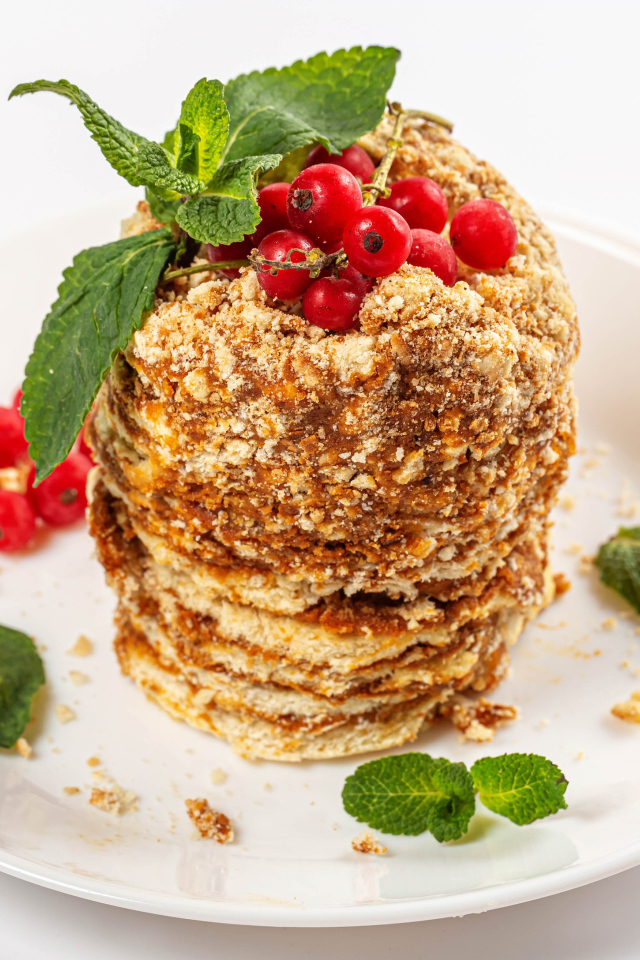 Вкусное пирожное со сгущенкой и ягодами красной смородины на белом фоне