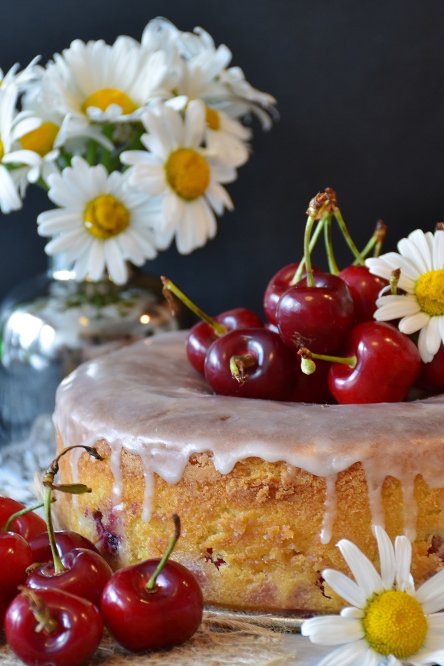 Свежий пирог вишней на столе с ромашками 