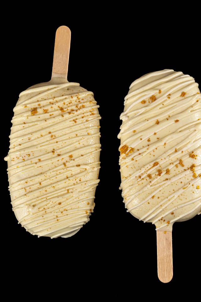 Мороженое на палочке в белом шоколаде на черном фоне
