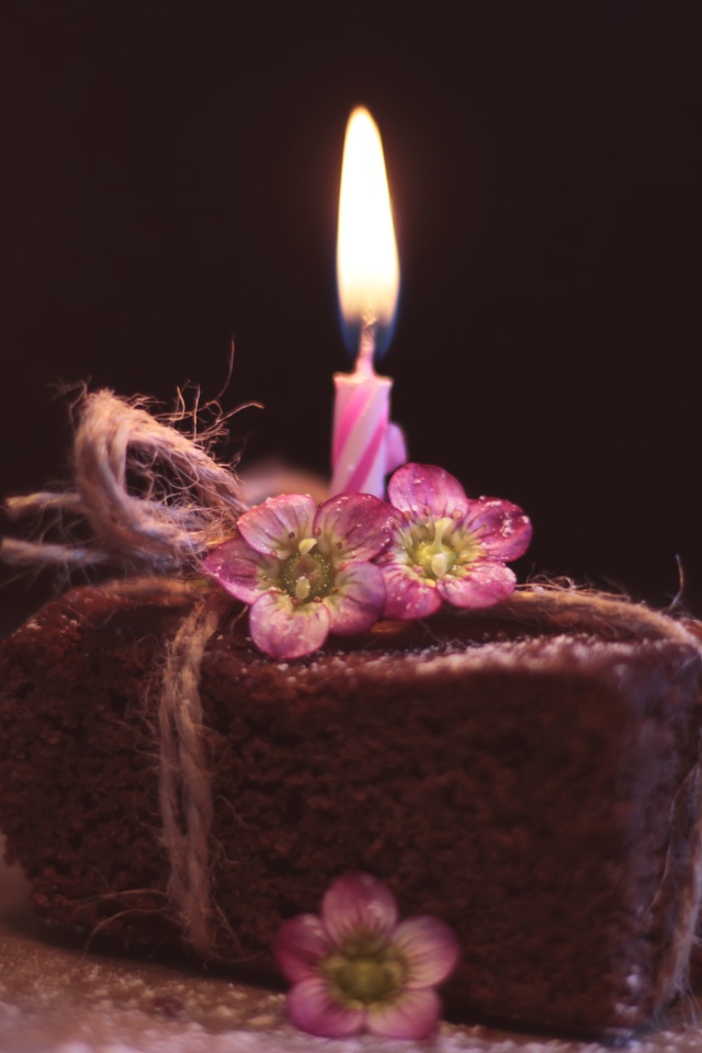 Кусок торта на столе с розовыми цветами и свечкой