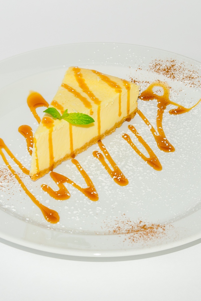 Кусок чизкейка с сиропом на большой белой тарелке 