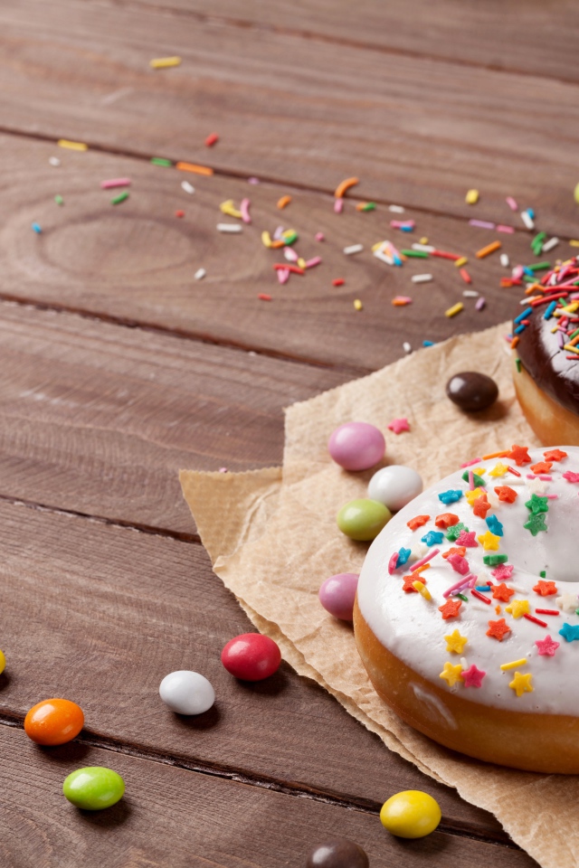 Сладкие пончики с глазурью на столе с конфетами