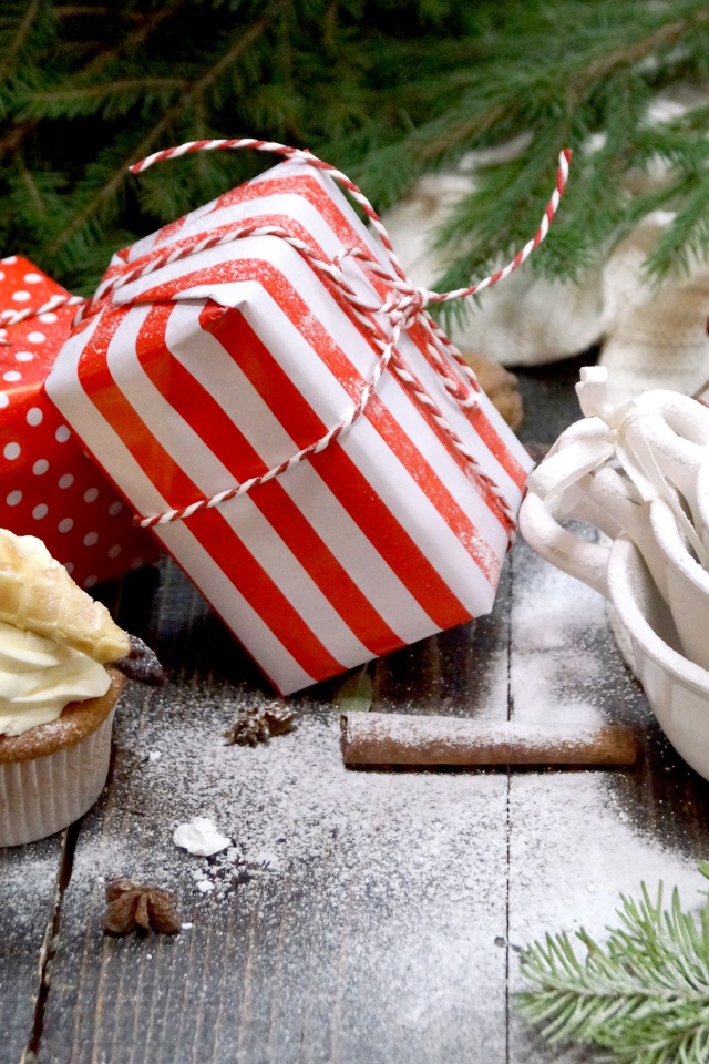 Два подарка на столе с еловой веткой и кексами 