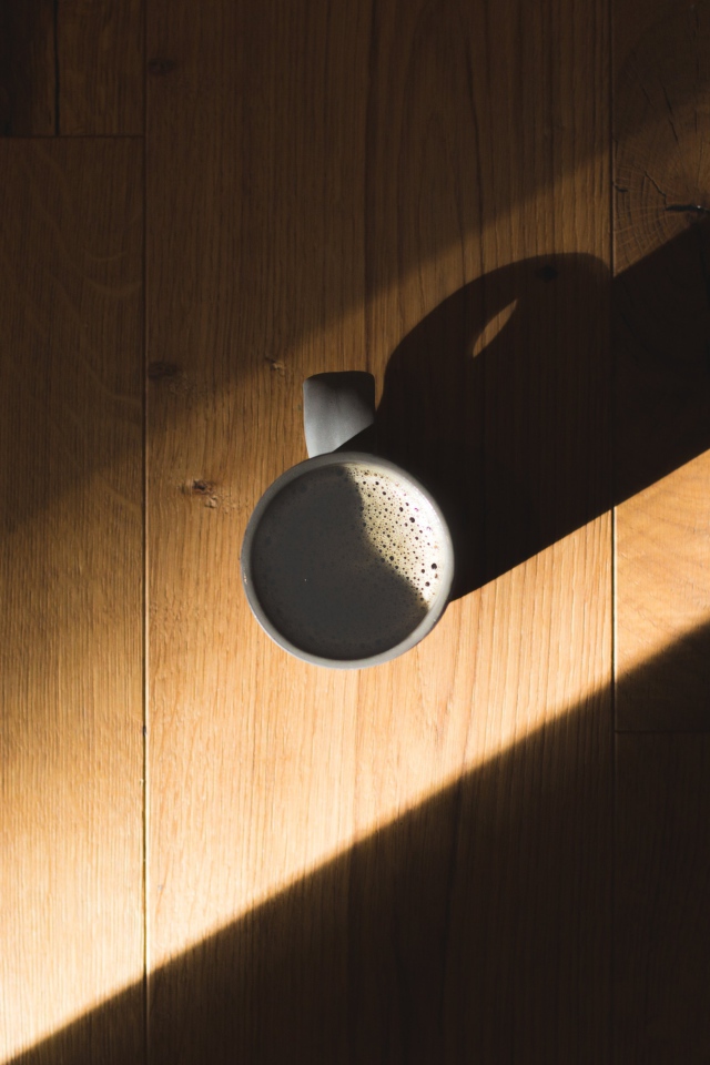 Чашка кофе стоит на столе в лучах солнца
