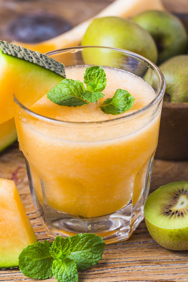 Стакан сока на столе с киви и дыней