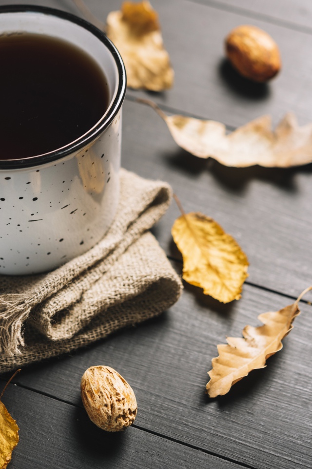 Кружка кофе на столе с листьями и пледом