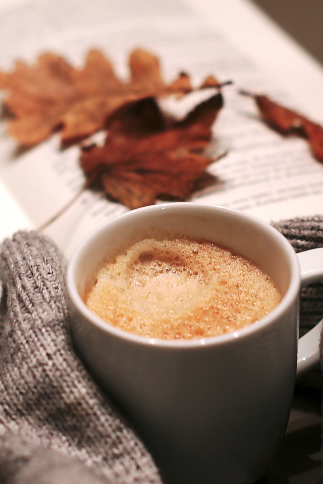 Чашка горячего кофе на столе с книгой 