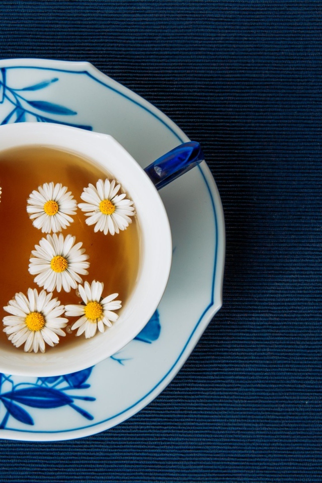 Чашка горячего чая с ромашкой на столе