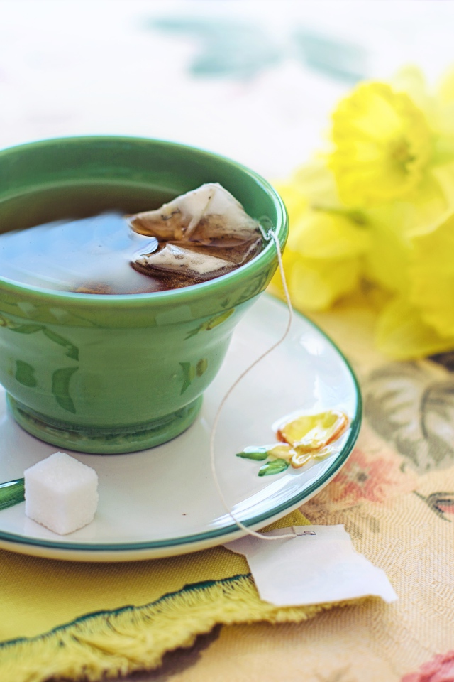 Чашка чая на столе с сахаром и нарциссами