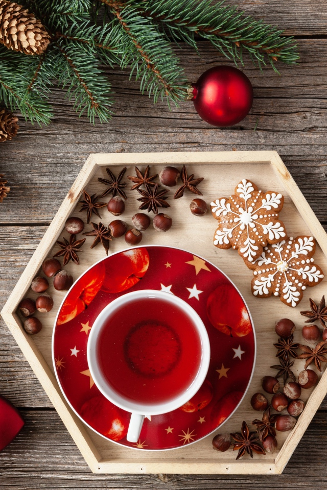 Чашка чая с печеньем и орехами на столе с еловой веткой