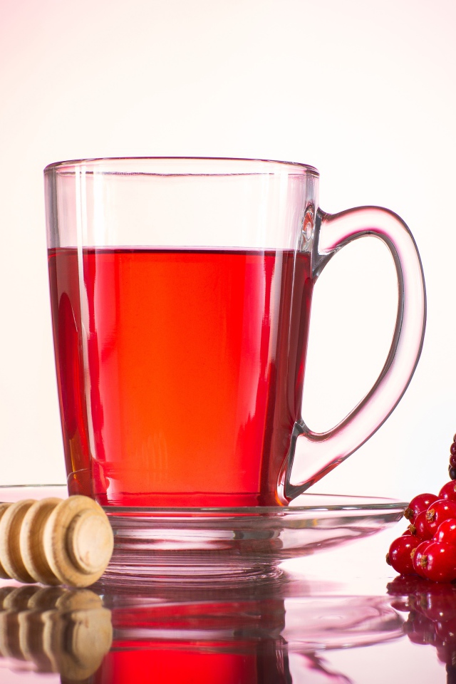 Чашка чая с медом на столе с ягодами