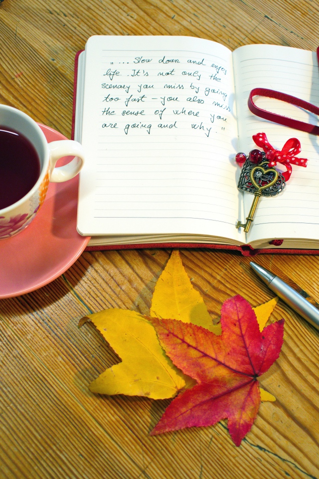 Чашка чая с блокнотом и листьями на столе 