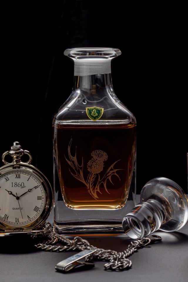 Дорогой коньяк на столе с карманными часами 
