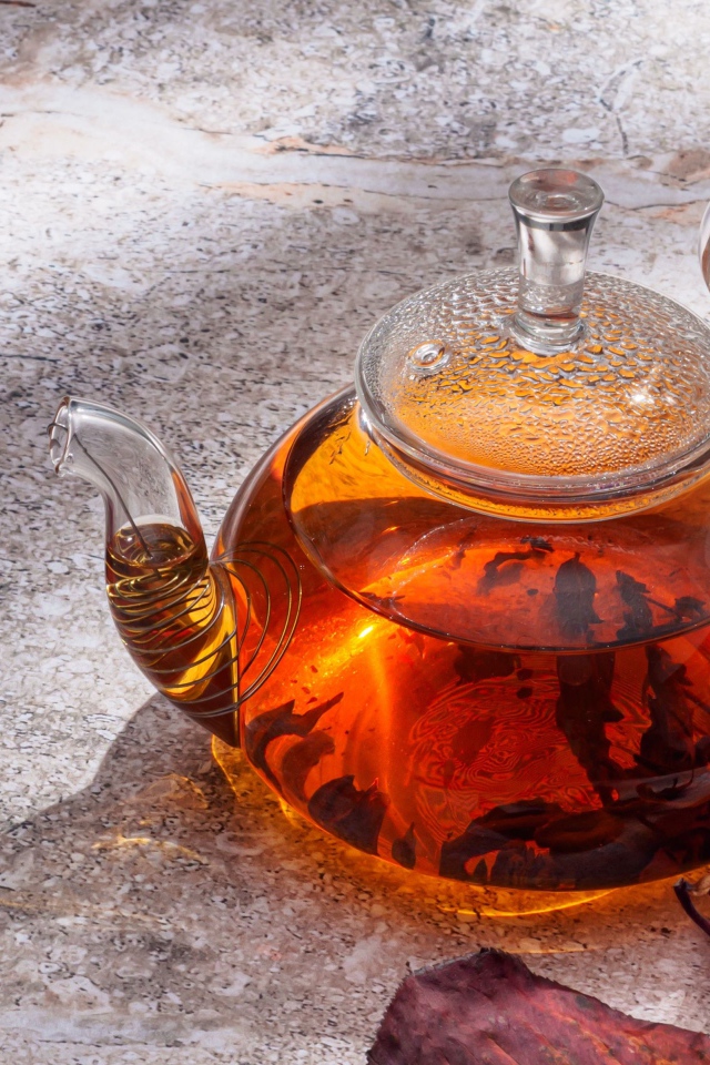 Стеклянный чайник на столе с листьями