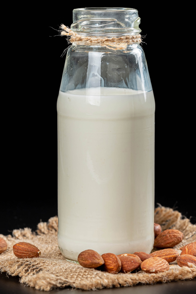 Молоко с миндалем на черном фоне