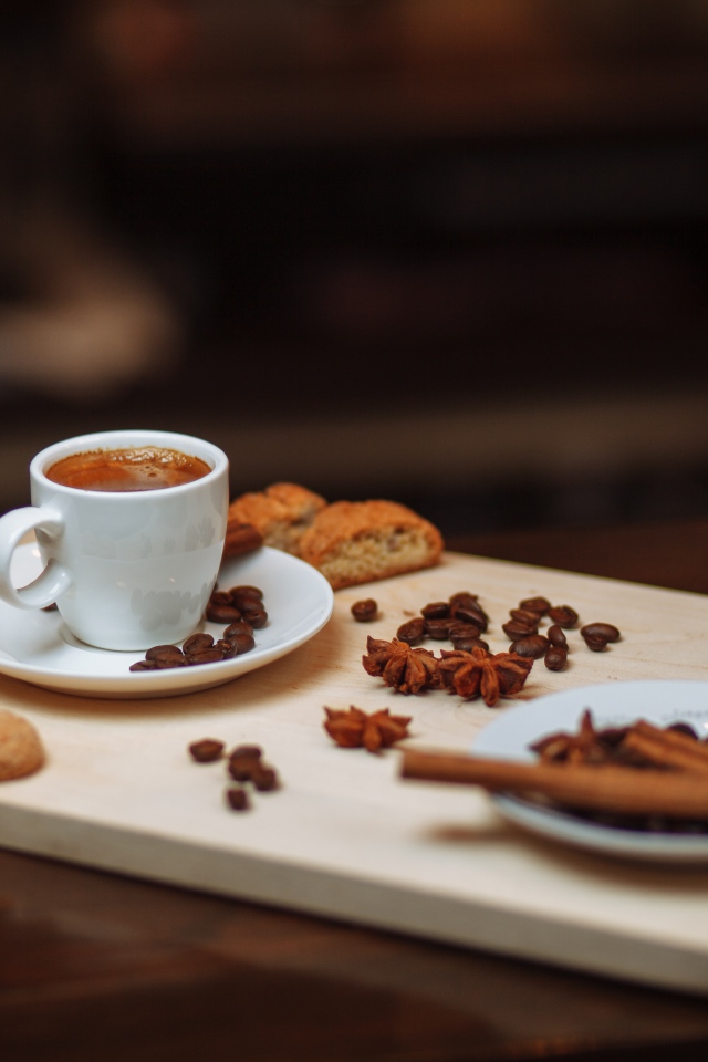 Маленькая чашка кофе на столе с корицей, бадьяном и печеньем 