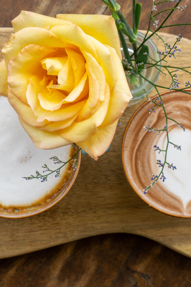 Две чашки капучино на столе с розой