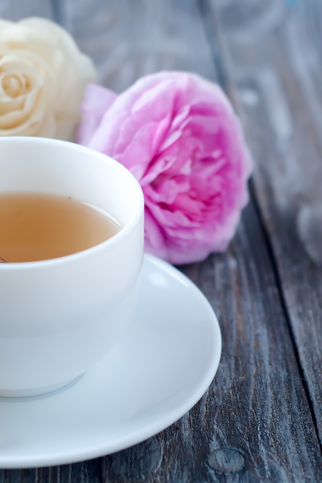 Белая чашка чая на деревянном  столе с розами