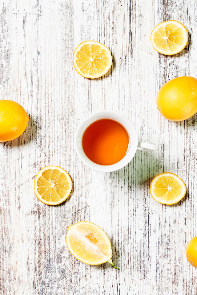 Желтые лимоны с чаем на белом столе 