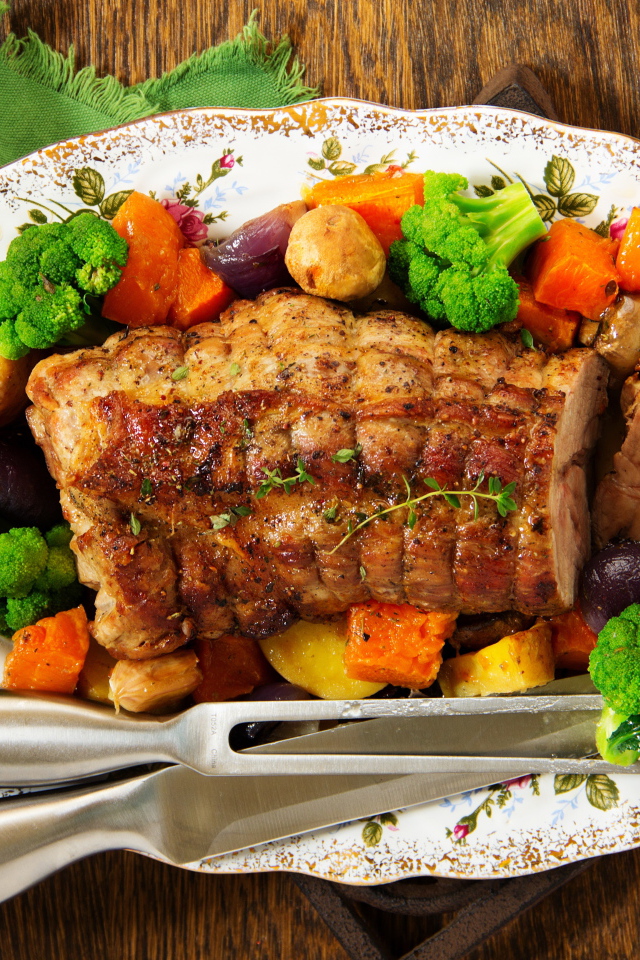 A piece of baked pork on a plate with vegetables