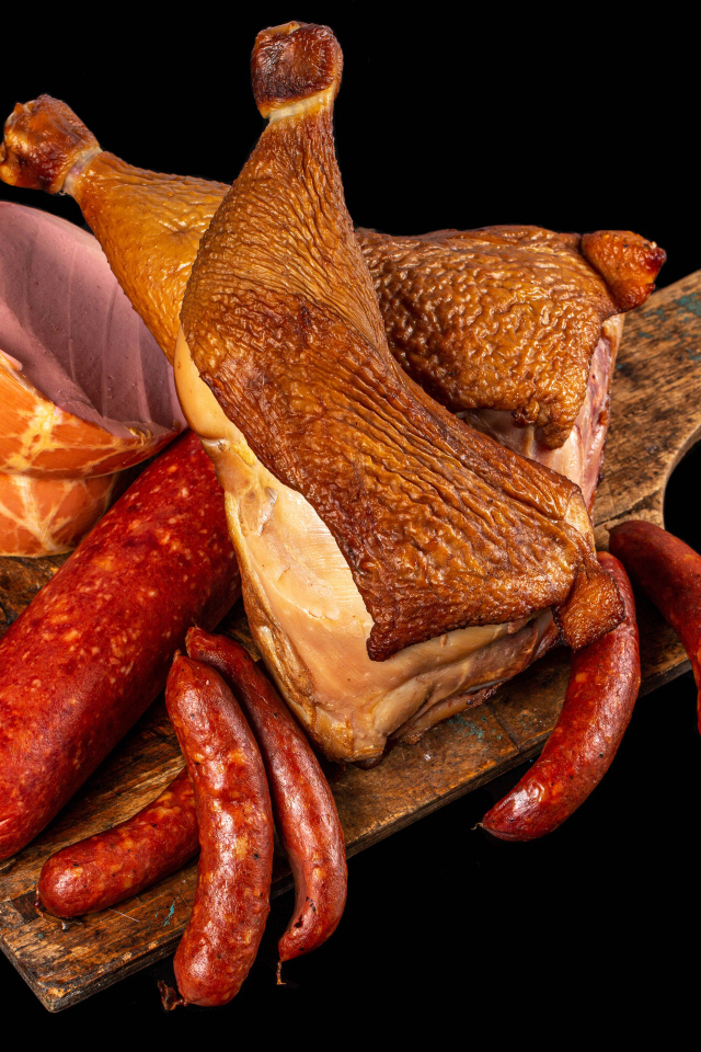 Appetizing smoked meats and sausage on a black background