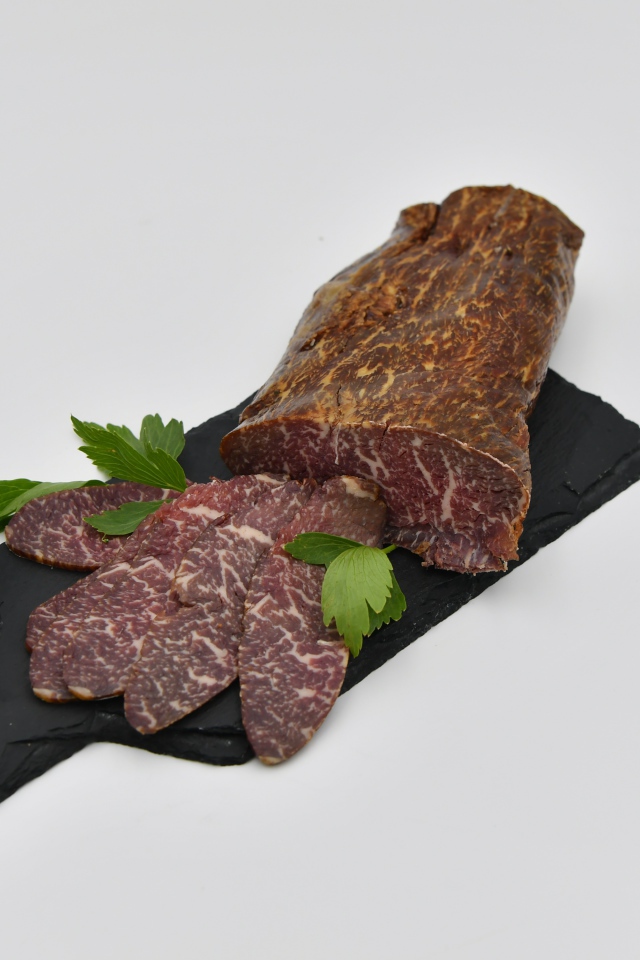 Вяленое мясо на доске на сером фоне