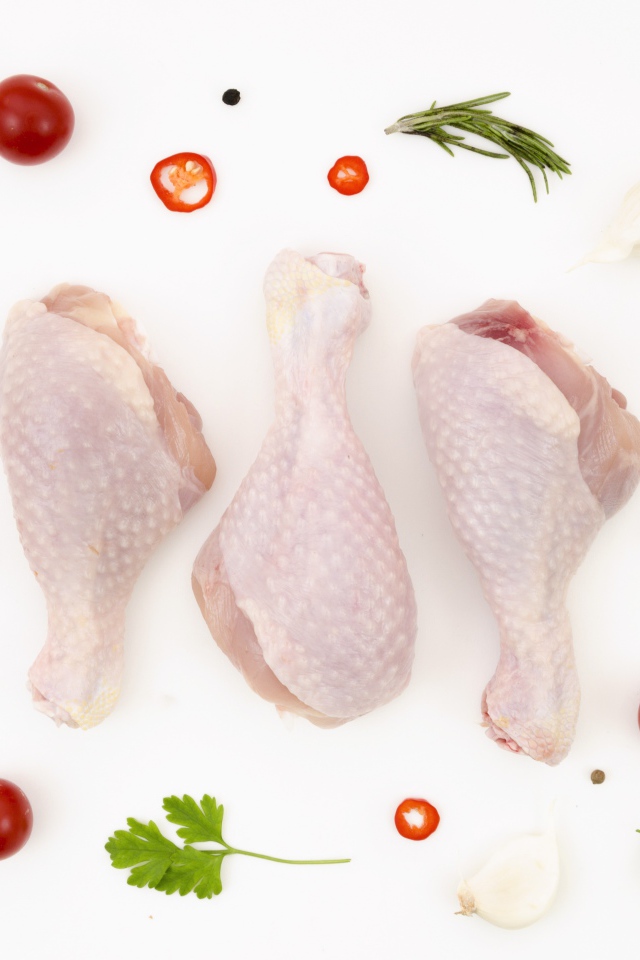 Свежие куриные бедра с перцем и помидорами на белом фоне 