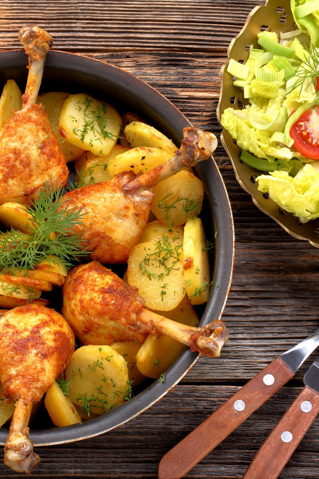 Fried chicken legs with potatoes on a table with salad