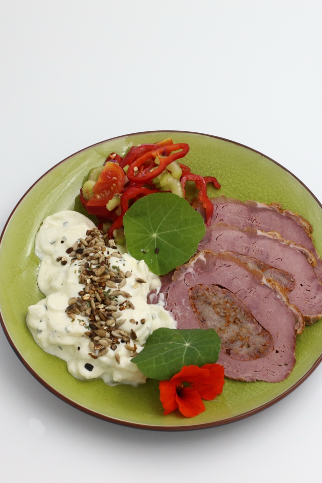 Мясо с соусом и овощами на тарелке на сером фоне