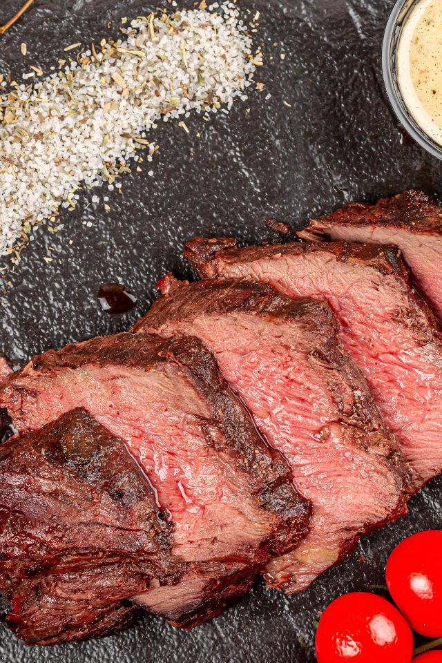 Мясо с помидорами и соусами на доске 