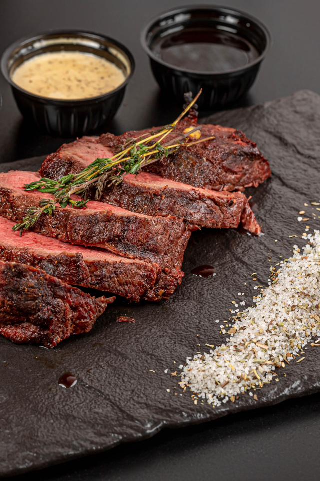 Кусок запеченного мяса на доске с кукурузой и специями 