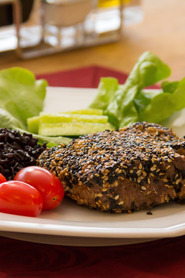 Кусок мяса на тарелке с рисом и овощами 