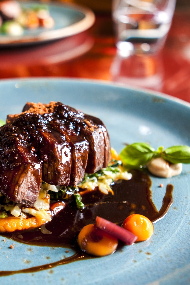 Кусок мяса с соусом на тарелке в ресторане