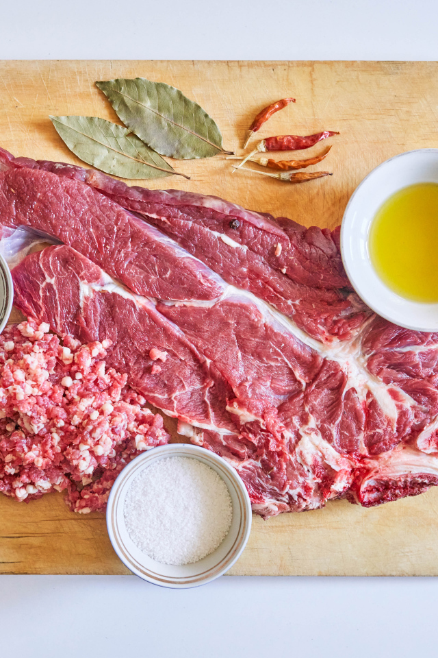 Кусок мяса со специями и оливковым маслом на доске 