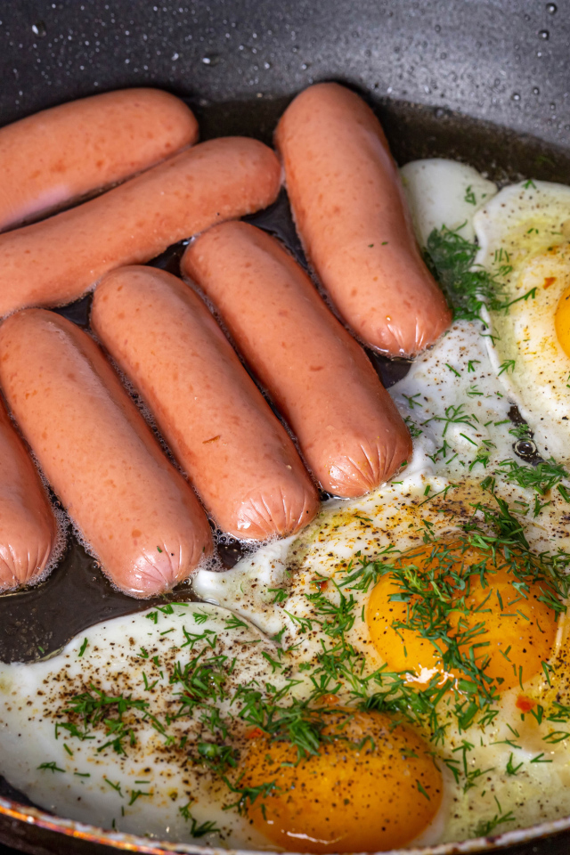 Сосиски с яичницей на сковороде
