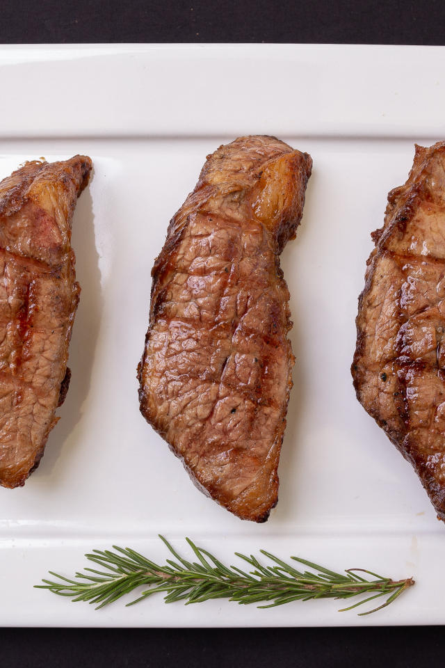 Три куска жареного мяса на большой белой тарелке