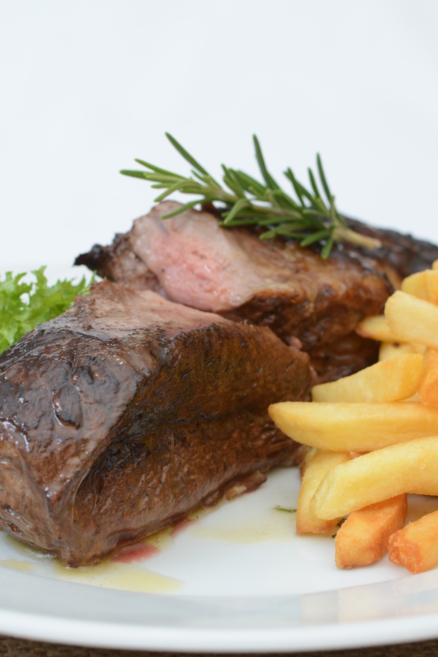 Два куска мяса на тарелке с картофелем фри 