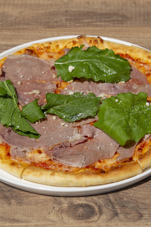 Пицца с кусочками мяса и зеленью на столе
