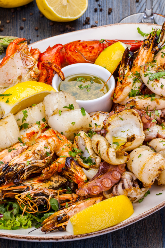 Запеченные морепродукты на тарелке с лимоном 