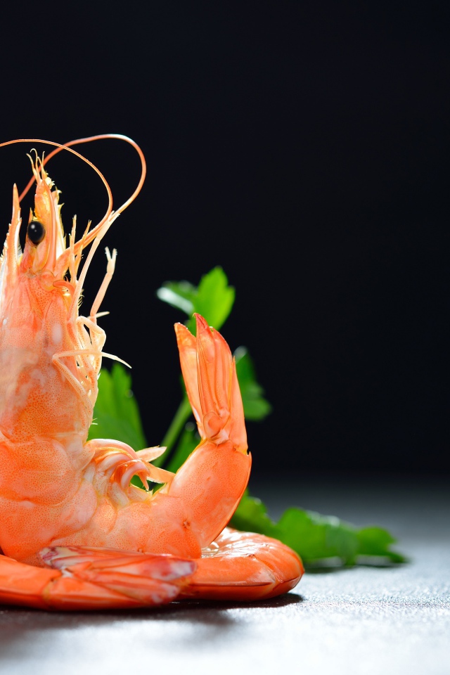 Вареные креветки с лимоном на черном фоне