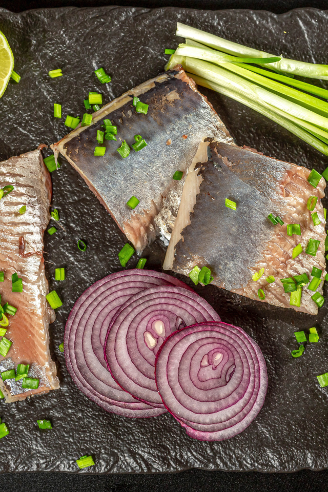 Куски сельди с луком и кусочками лимона