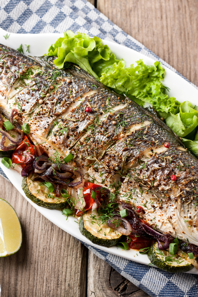 Большая запеченная рыба с кабачками и листьями салата