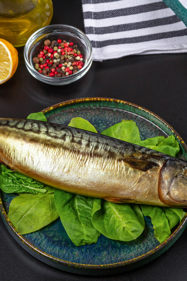 Большая копченая скумбрия на тарелке с базиликом