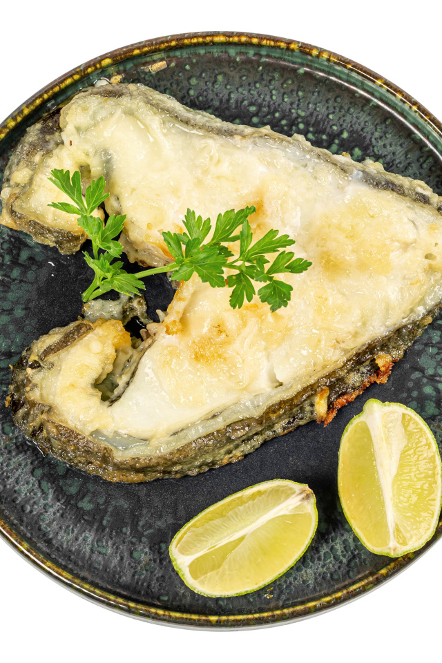 Кусок рыбы на тарелке с лимоном на белом фоне
