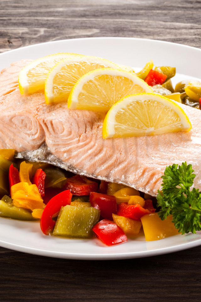 Кусок рыбы на тарелке с овощами и лимоном